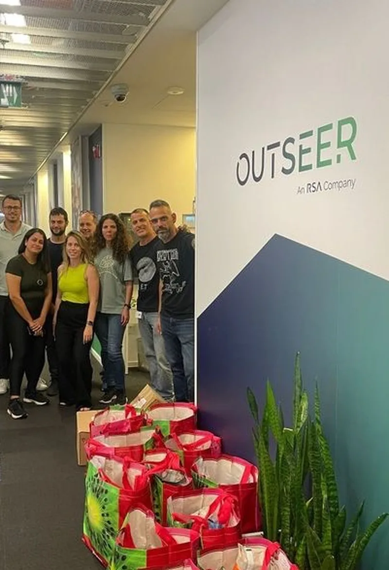 Outseer team photographed in front of the branded office wall.